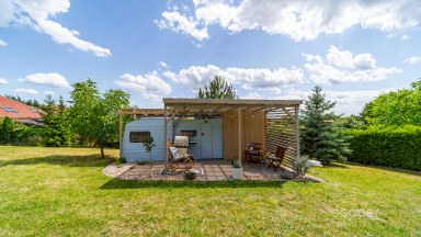 Příjemná venkovská zahrada s rekreačním karavanem a terasou.